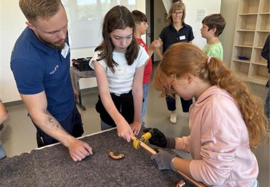 Sina und Sophie schneiden unter Anleitung von Seusta-Azubi Jakob Wisner ein Kupferrohr. Foto: Stehr